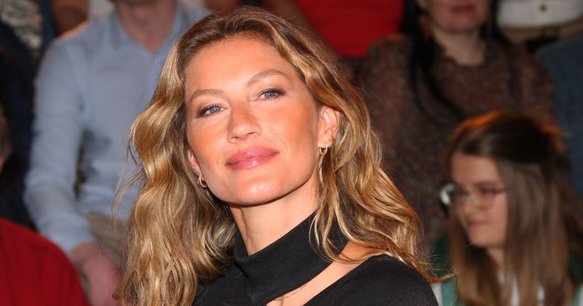 Gisele Bündchen mit offenen blonden Haaren und einem schwarzen Top.