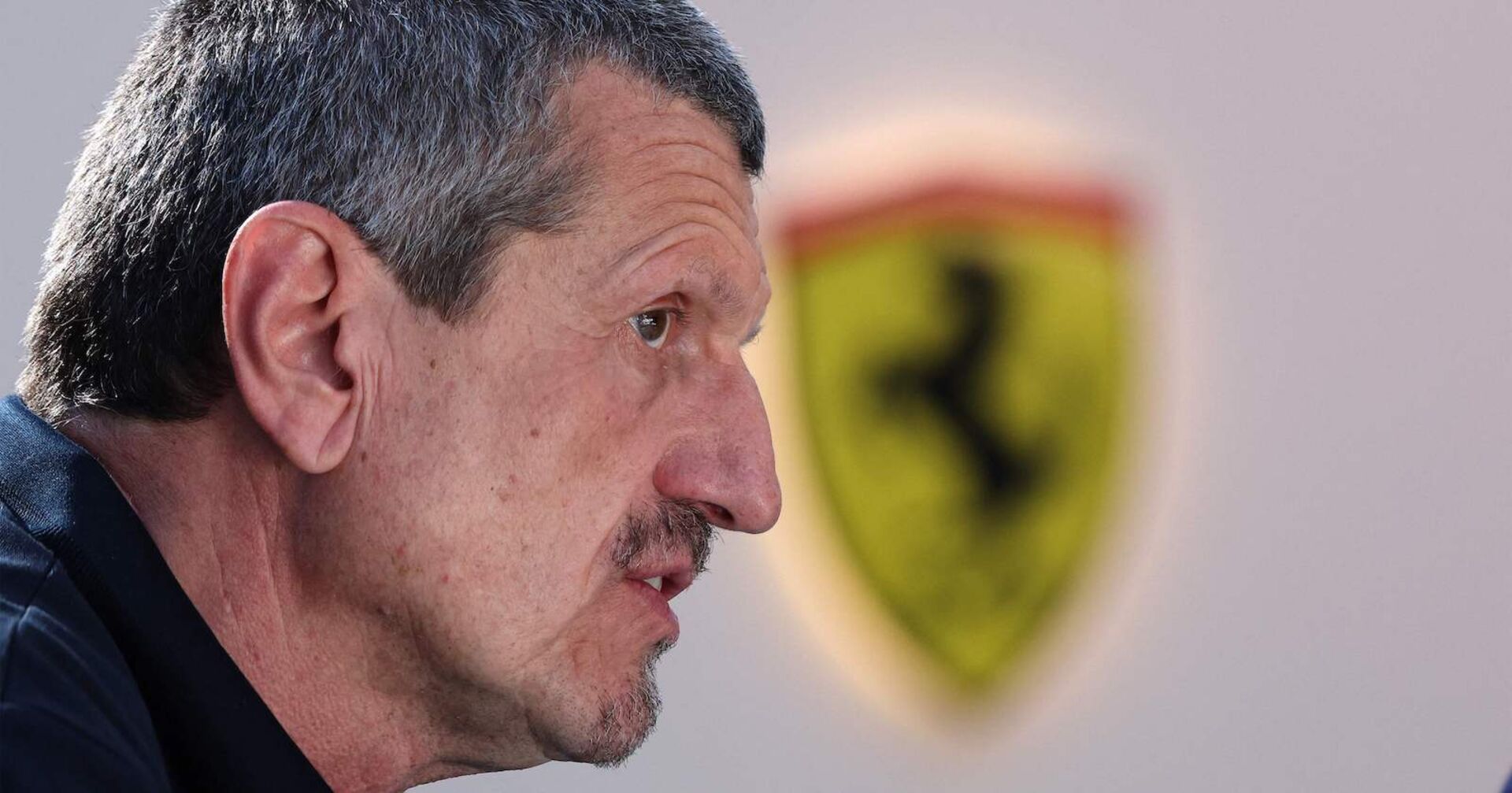 Guenther Steiner in Großaufnahme im Profil, im Hintergrund das Logo von Ferrari