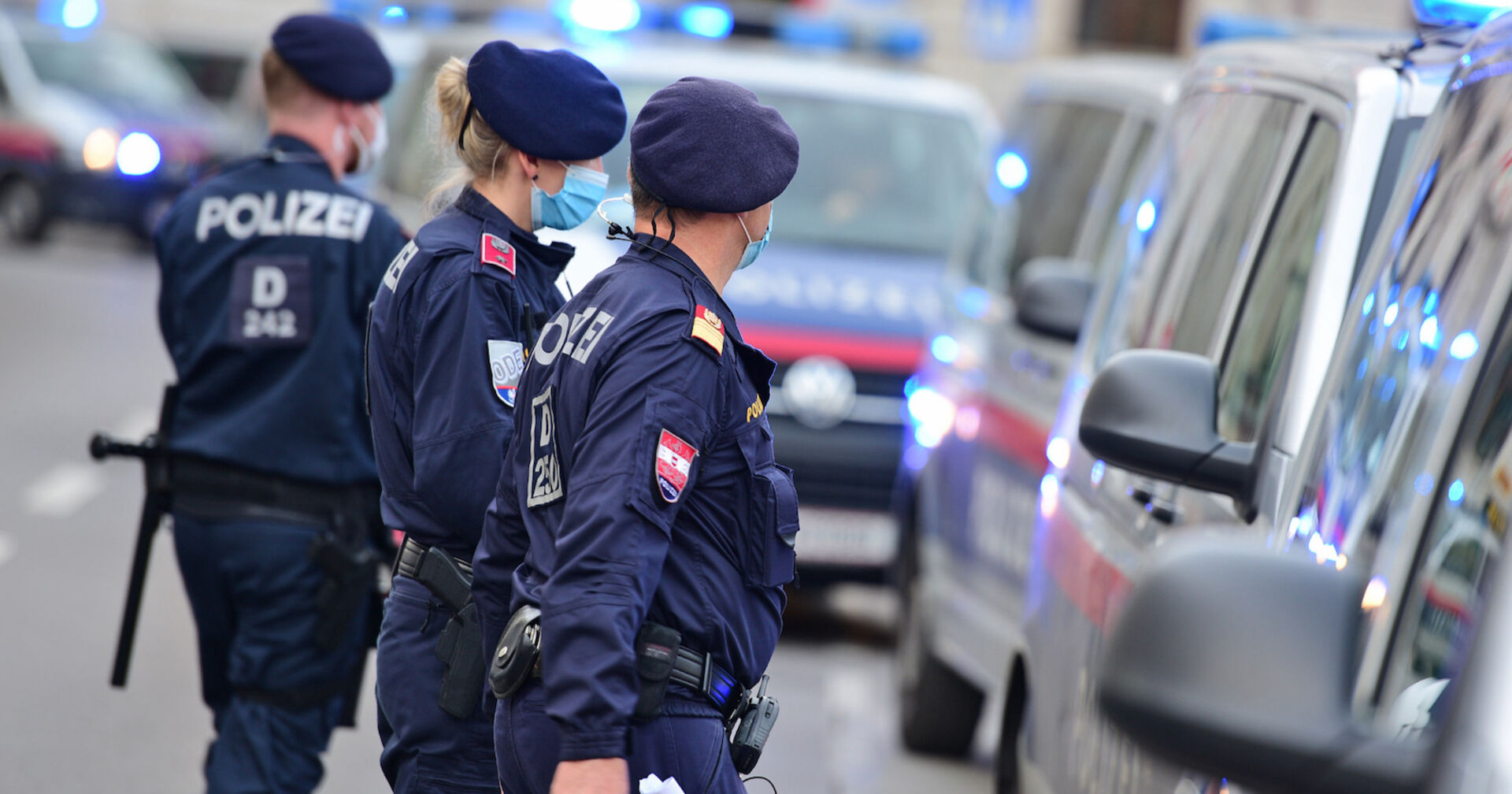 Polizisten gehen auf ihre Einsatzfahrzeuge zu