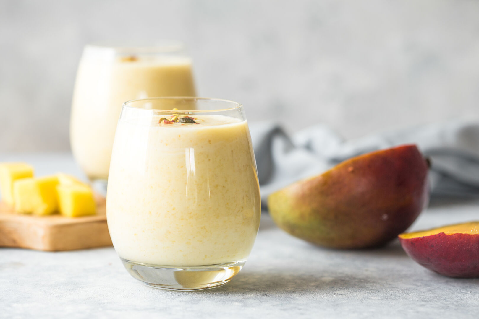 Glas gefüllt mit hellgelben Mango-Kokosmilch-Smoothie