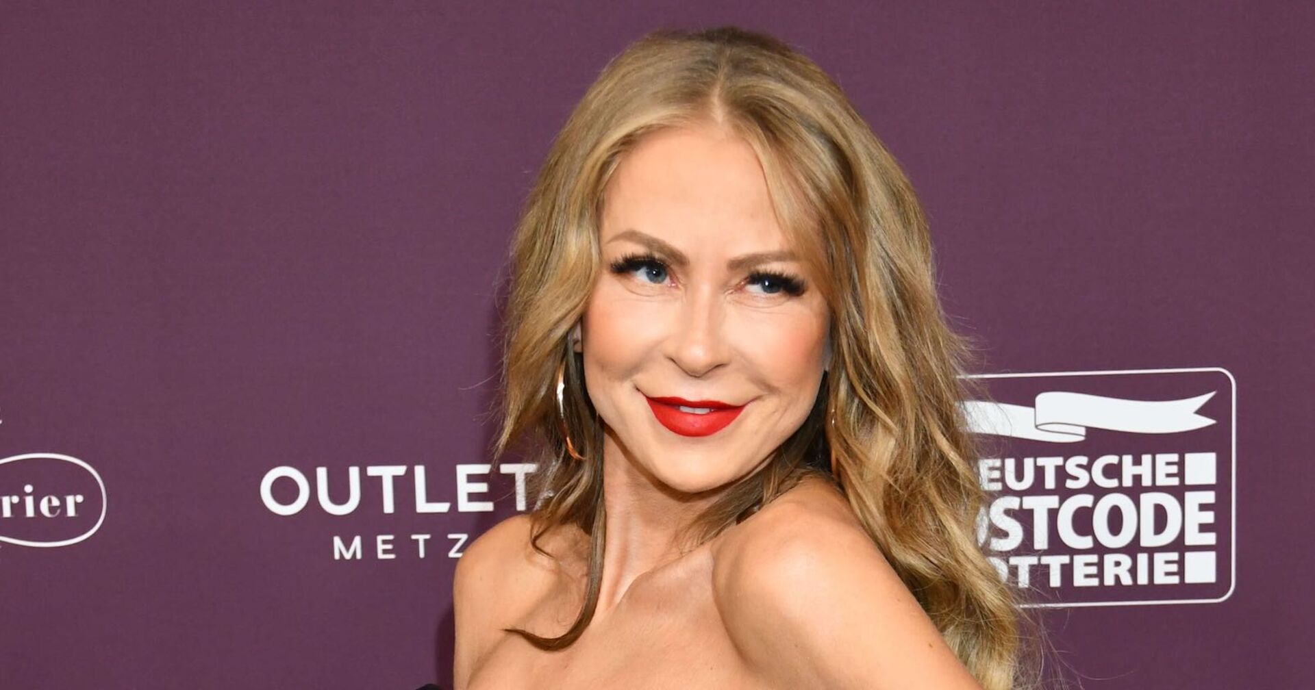 Jenny Elvers mit roten Lippenstift und offenen Haaren auf dem roten Teppich.