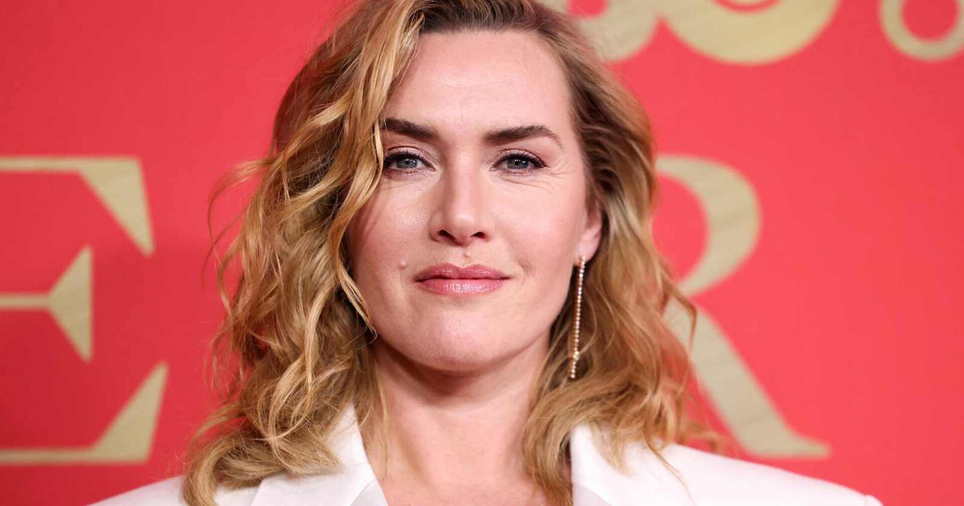 Kate Winslet mit einem weißen Blazer und blonden, gewellten Haaren.