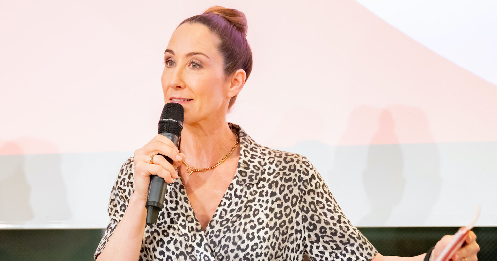 Kathi Bellowitsch mit einem Mikrofon auf einem Podium.