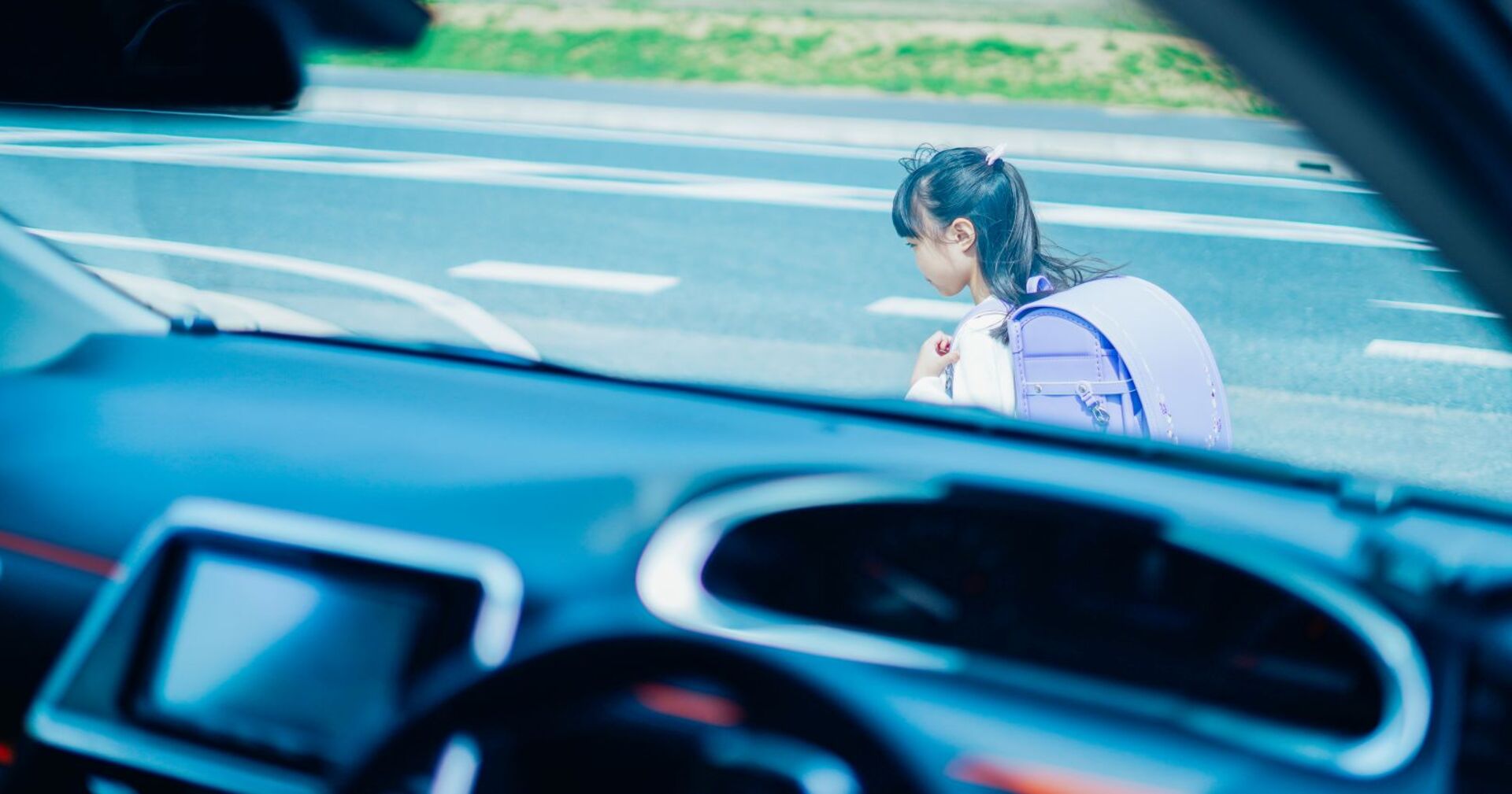 Jemand beobachtet ein kleines Mädchen von einem Auto aus.