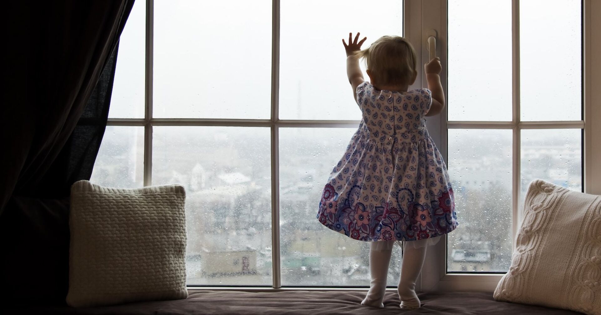 Ein kleines Mädchen steht an einem Fenster.