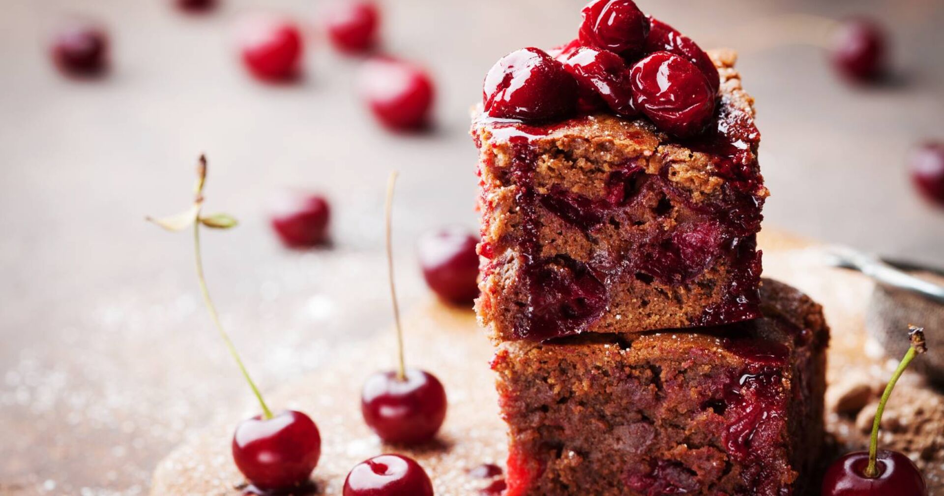 Seitenansicht von übereinander gestapelten Schokoladenkuchenstücken, die mit Kirschen dekoriert sind.