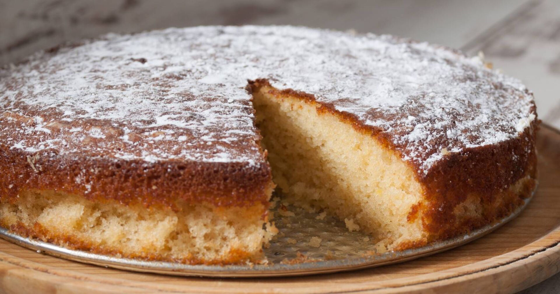 Angeschnittener Kuchen auf einem Servierteller, bei dem bereits ein Stück fehlt