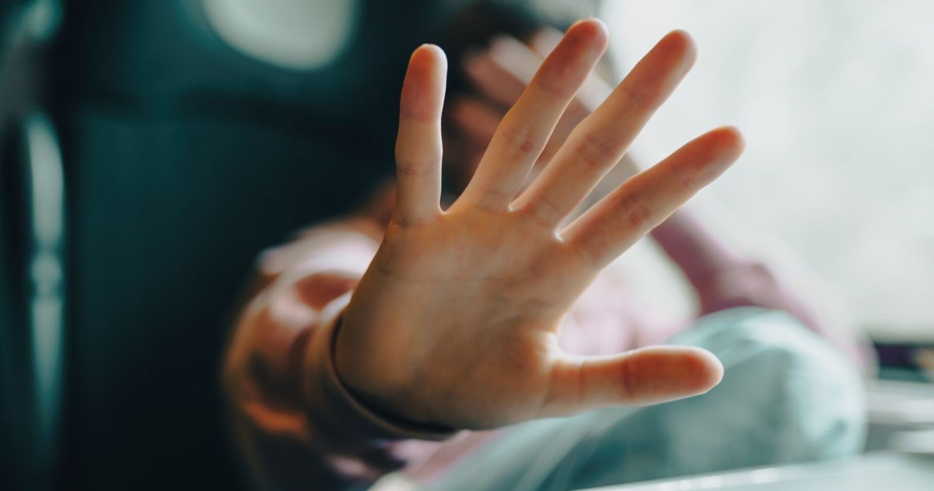Ein Mädchen signalisiet mit einer ausgestreckten Hand &quot;Stopp&quot;. Die andere hat sie verzweifelt über ihr Gesicht gelg.