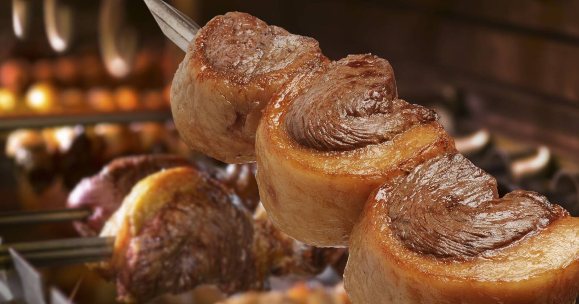 Spieß mit drei Stück Tafelspitz mit Fettdeckel über offener Flamme, gegrillt.