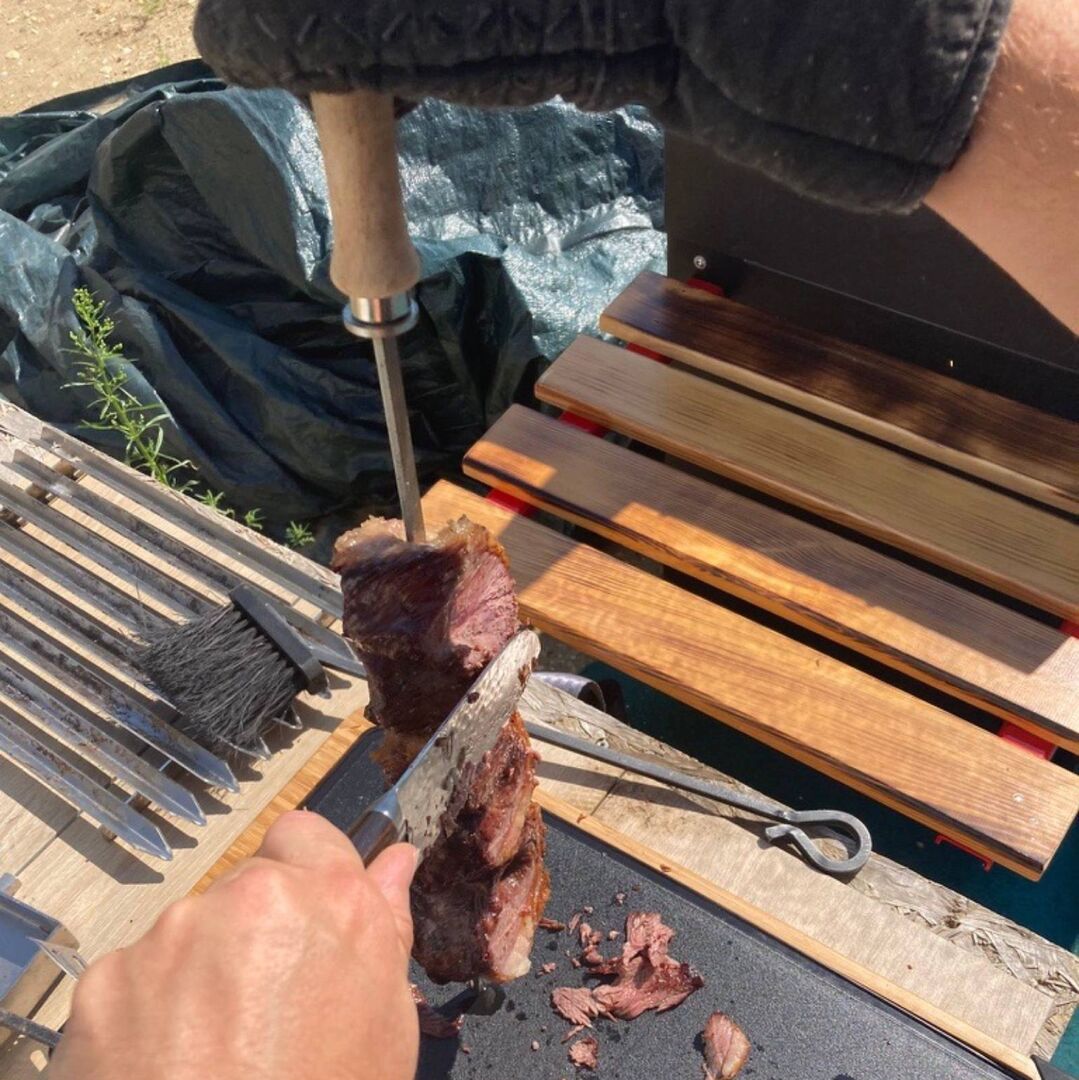 Picanha-Spieß wird auf dem Grill geschnitten.