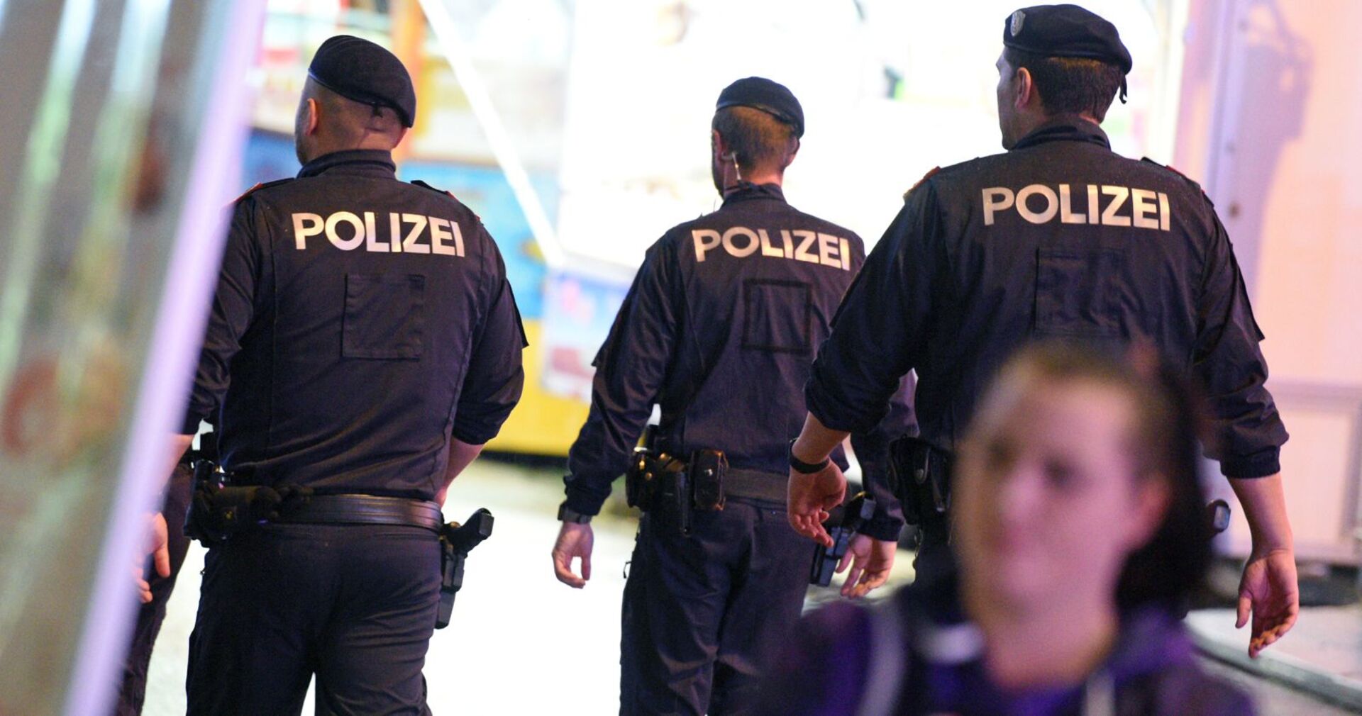 Drei Polizisten von hinten bei einem Einsatz.