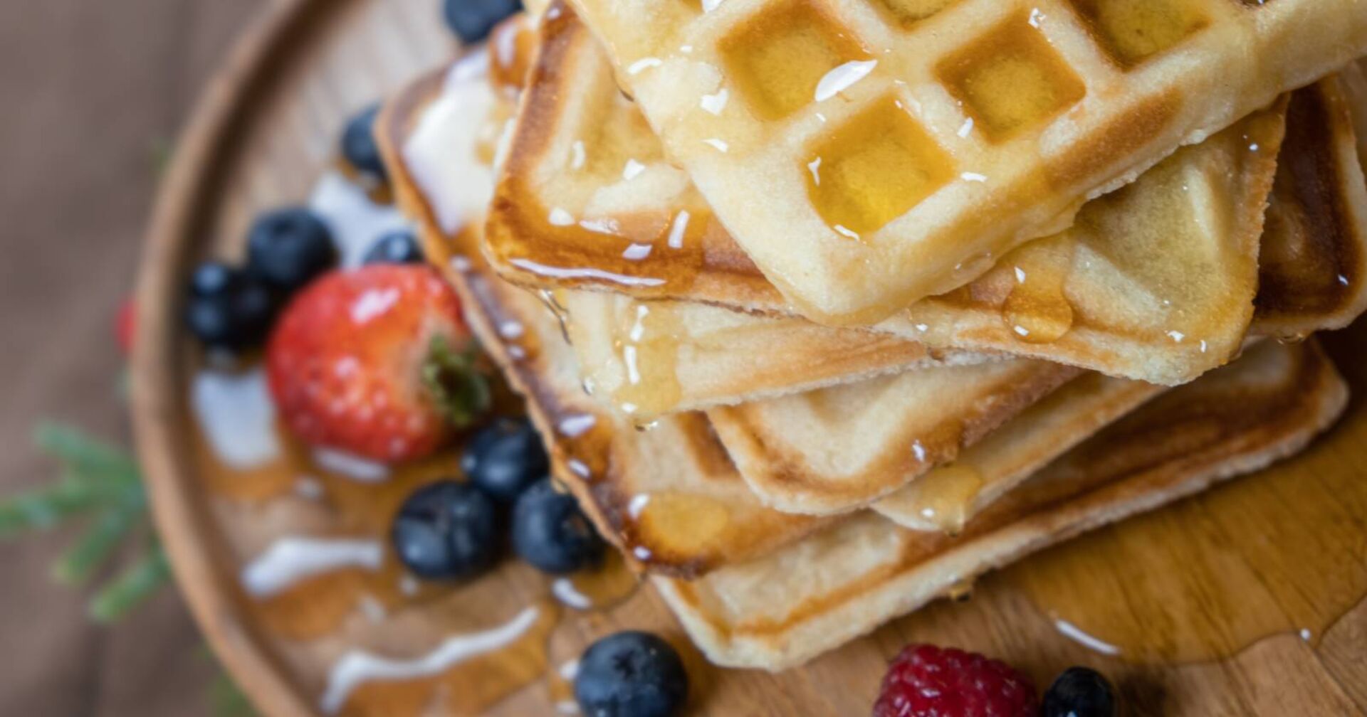 Teller mit knusprigen Waffeln, dekoriert mit Ahornsirup und Früchten.