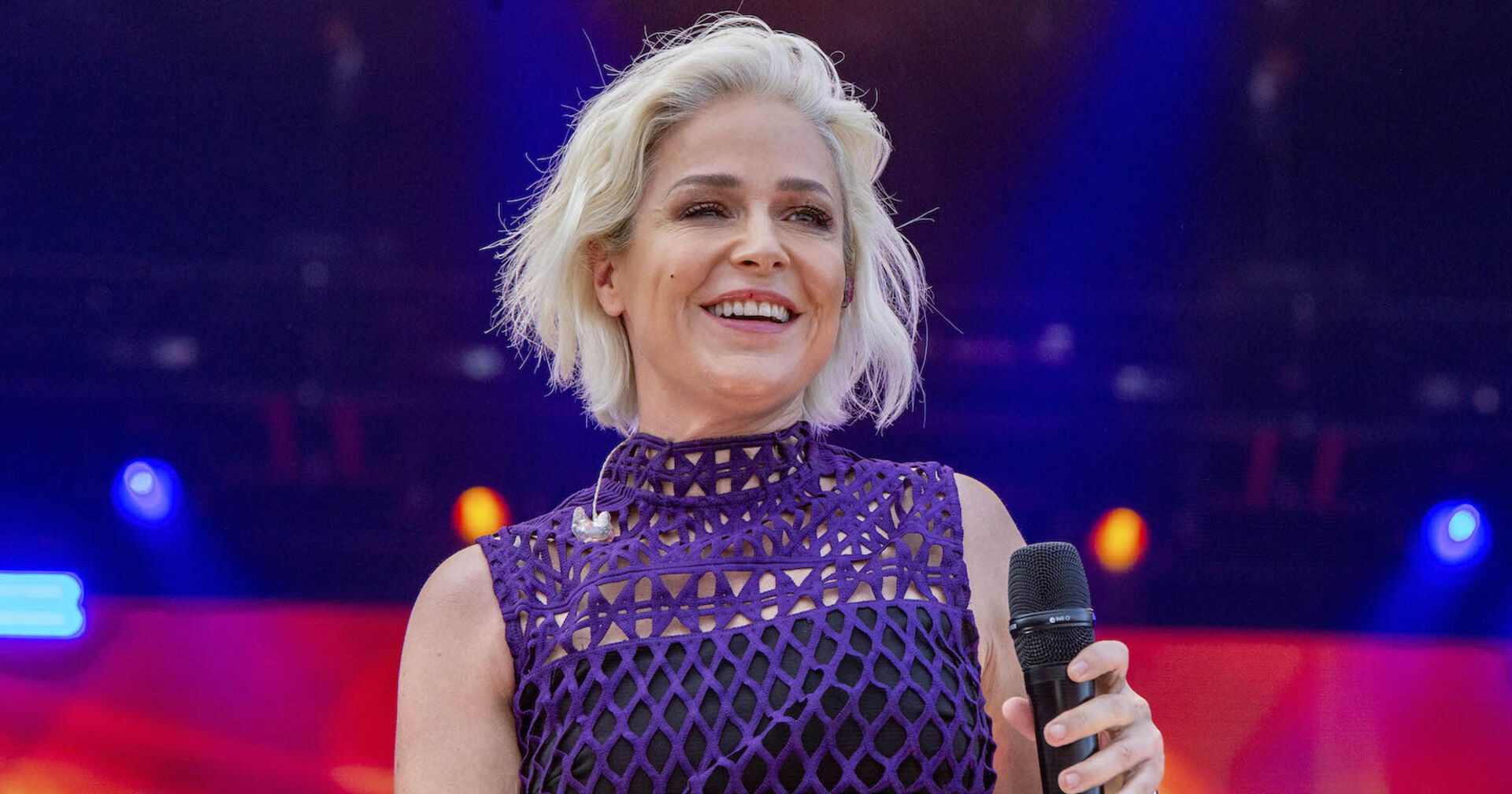 Schlagerstar Michelle mit einem violetten Oberteil und einem Mikrofon auf der Bühne.