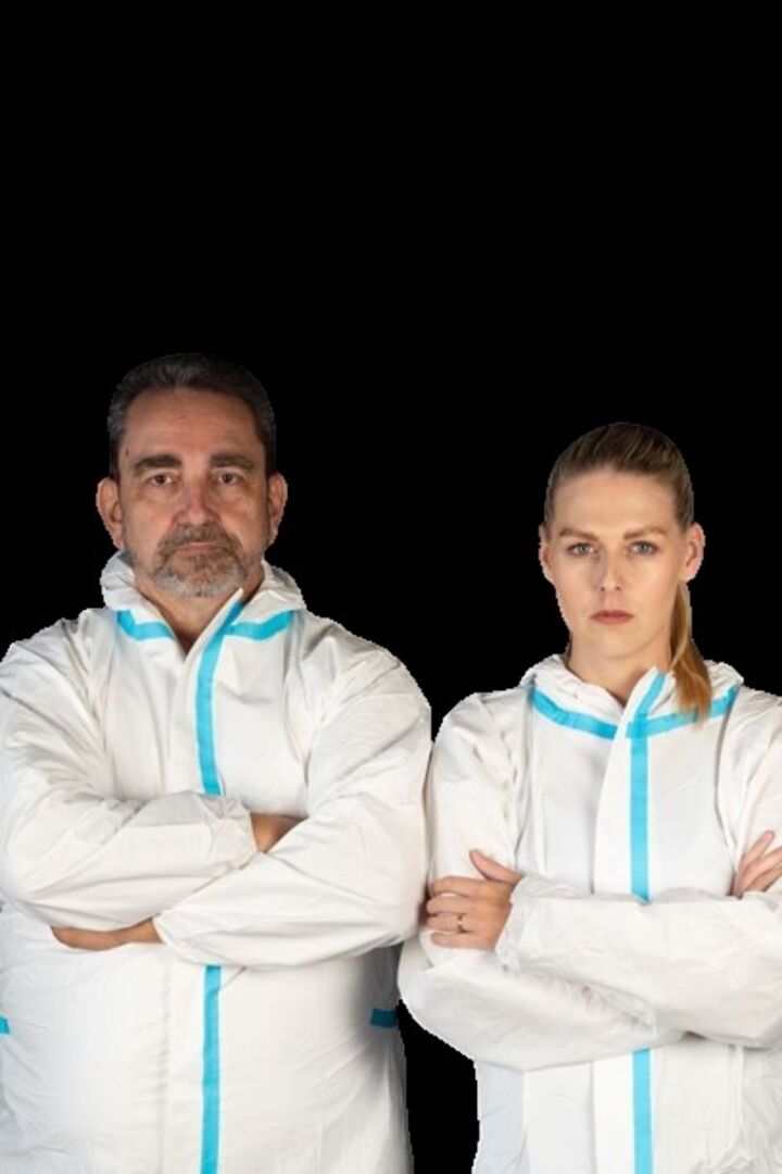 Andreas Karwas &amp; Kamila Horvath-Karwas in weißen Arbeitsanzügen vor schwarzem Hintergrund.