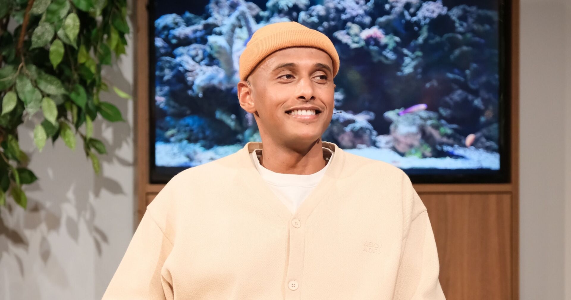 Teddy Teclebrhan mit einer beigen Mütze und einem weißen Pullover bei Willkommen Österreich.