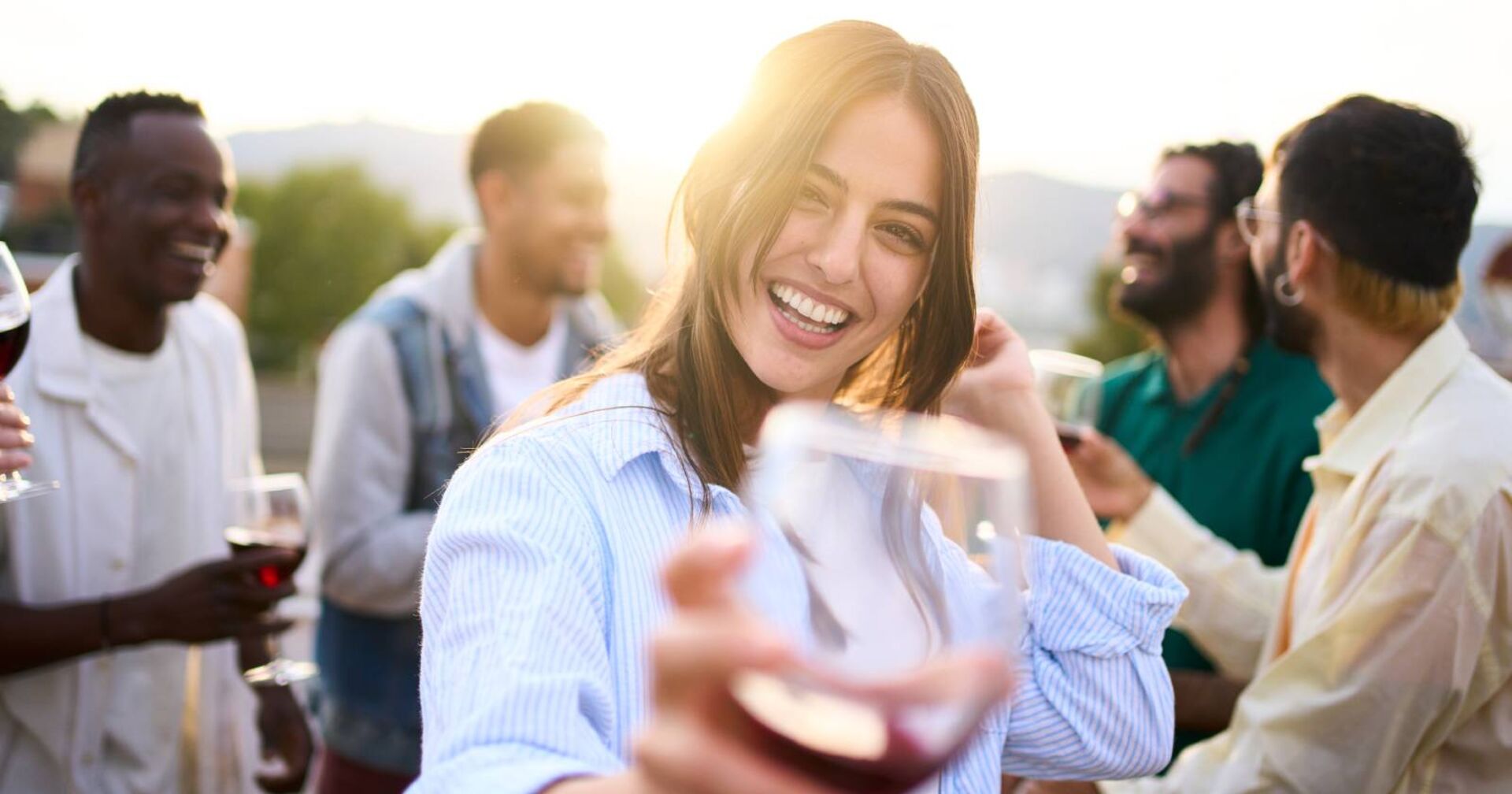 Frau hält lachend ihr Weinglas in die Kamera