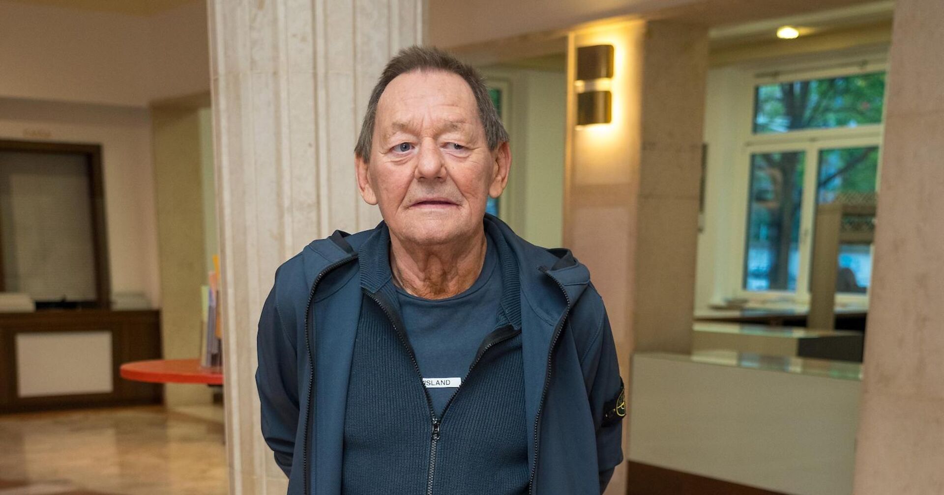 Wolfgang Ambros mit einem blauen Outfit in einem Gebäude