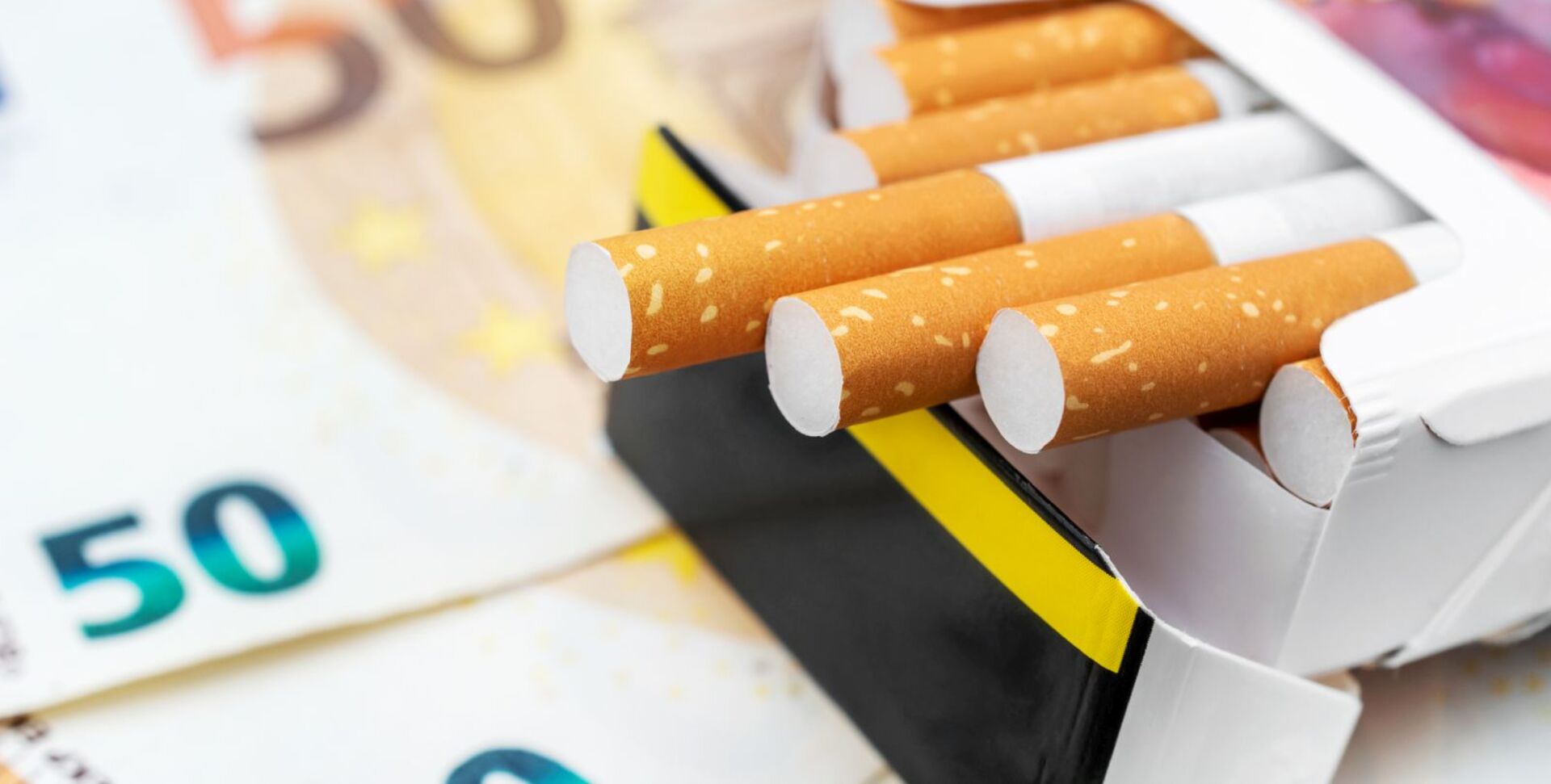 Zigaretten, die auf Geldscheinen liegen.