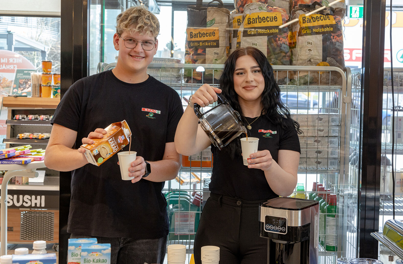 Ein Bub und ein Mädchen schütten Getränke in Becher