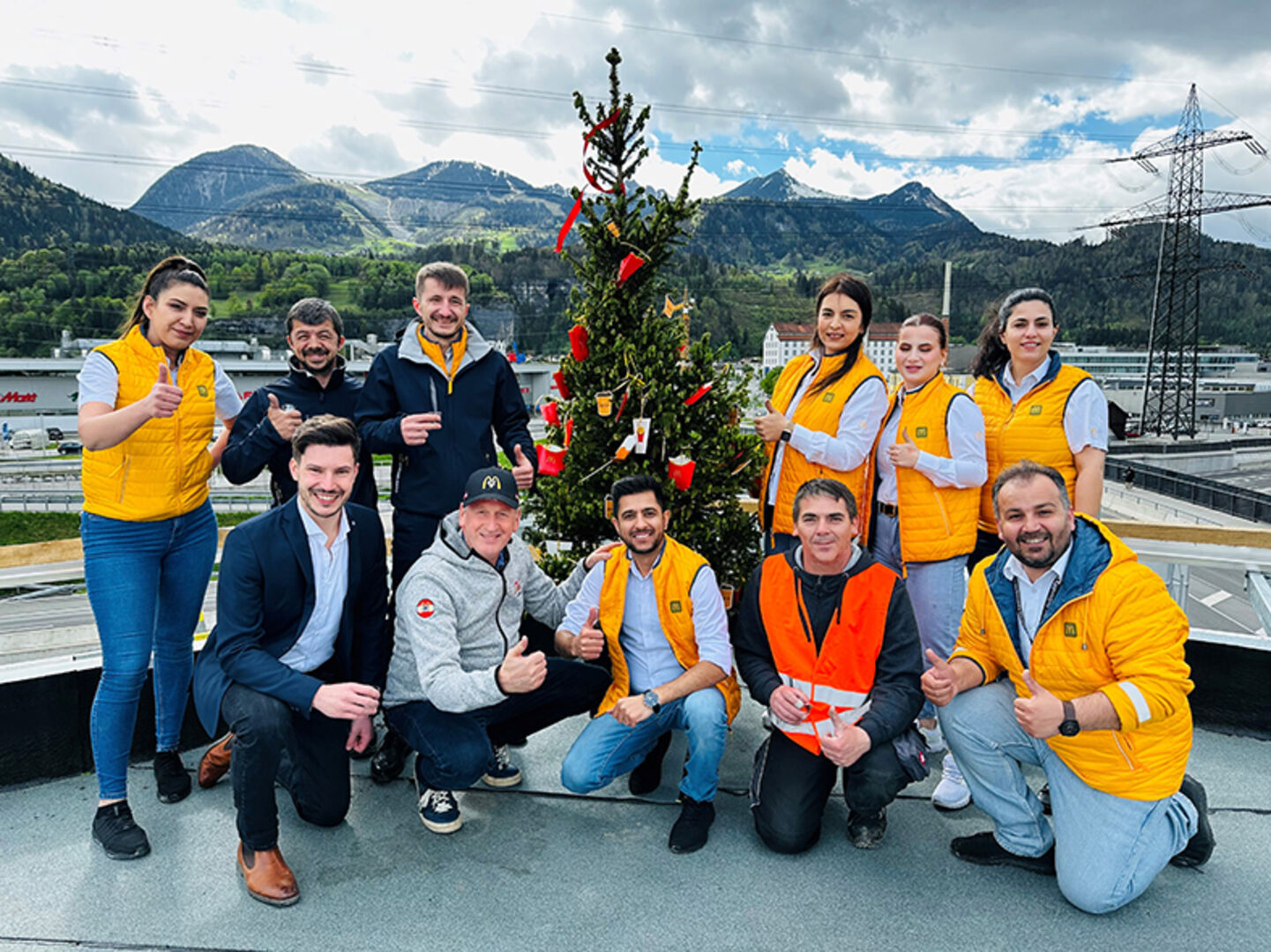 Das McDonald’s Vorarlberg Team mit dem Firstfeier Baum auf dem fertigen Dach des Neubaus in Bürs.