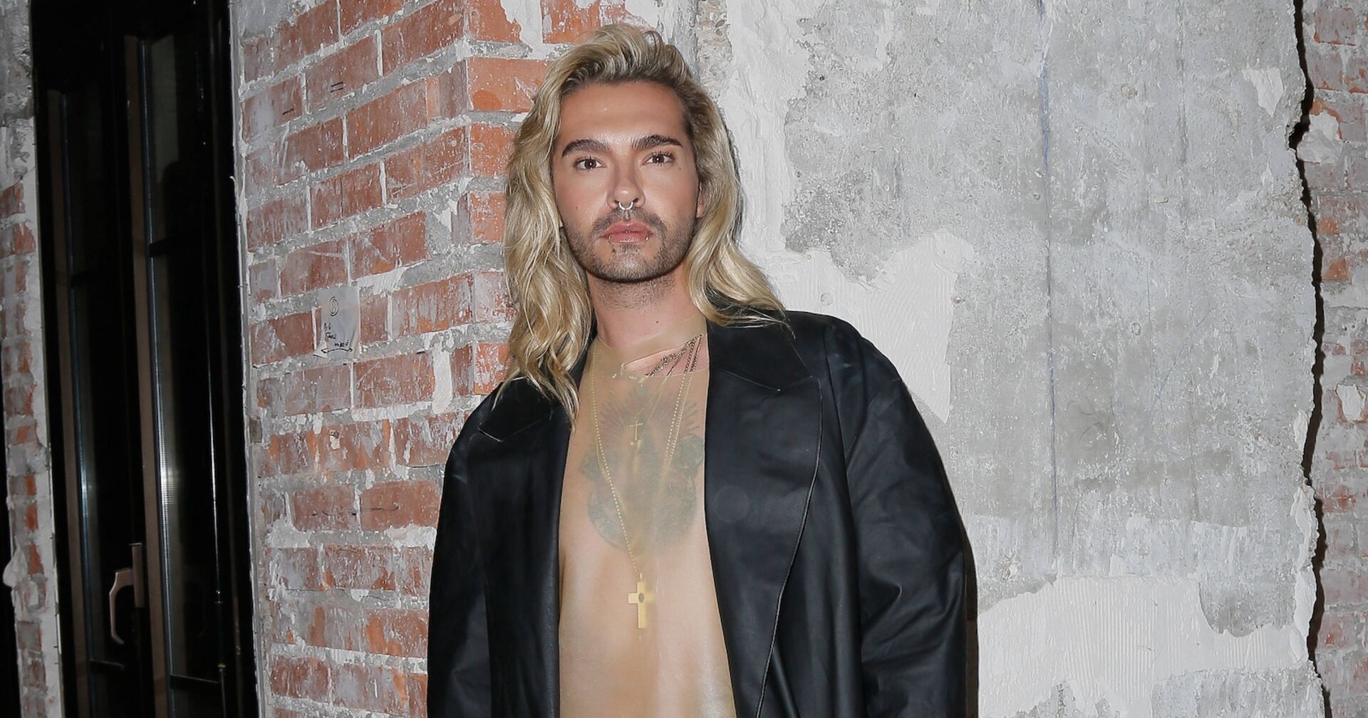 Bill Kaulitz mit gewellten blonden Haaren und einer schwarzen Lederjacke.