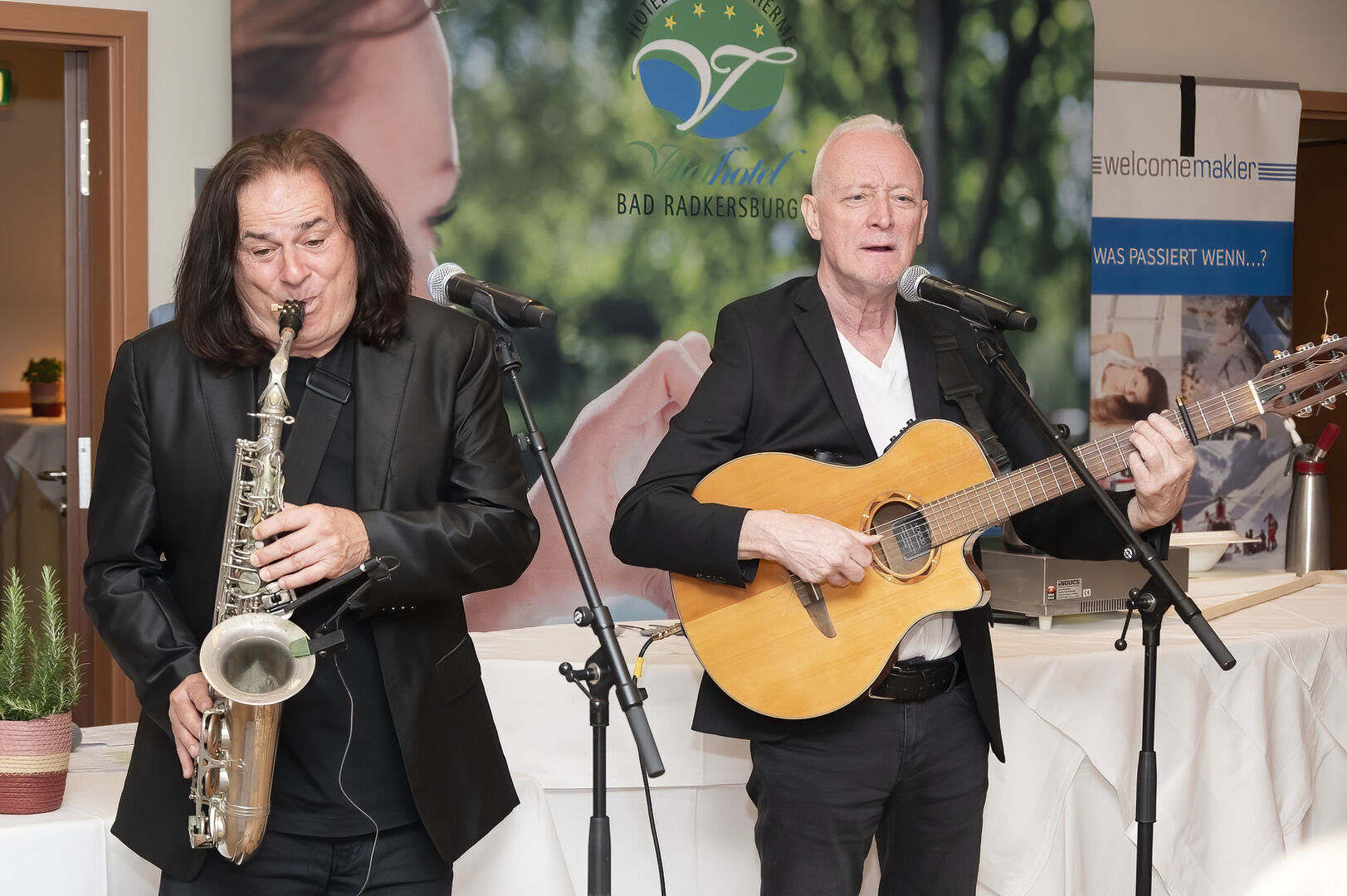 Zwei Männer stehen auf der Bühne und musizieren mit Saxophon und Gitarre
