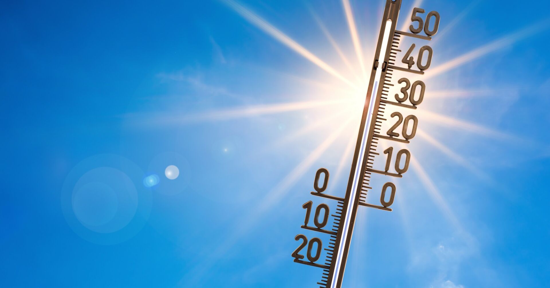 Ein Thermometer, im Hintergrund die strahlende Sonne.