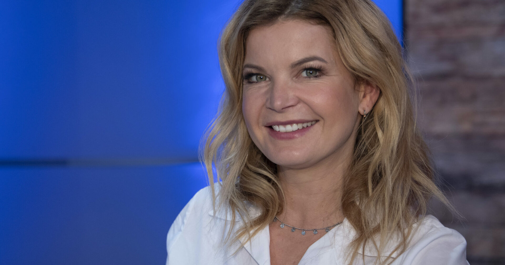 Eva Imhof mit einer weißen Bluse und gewellten blonden Haaren.
