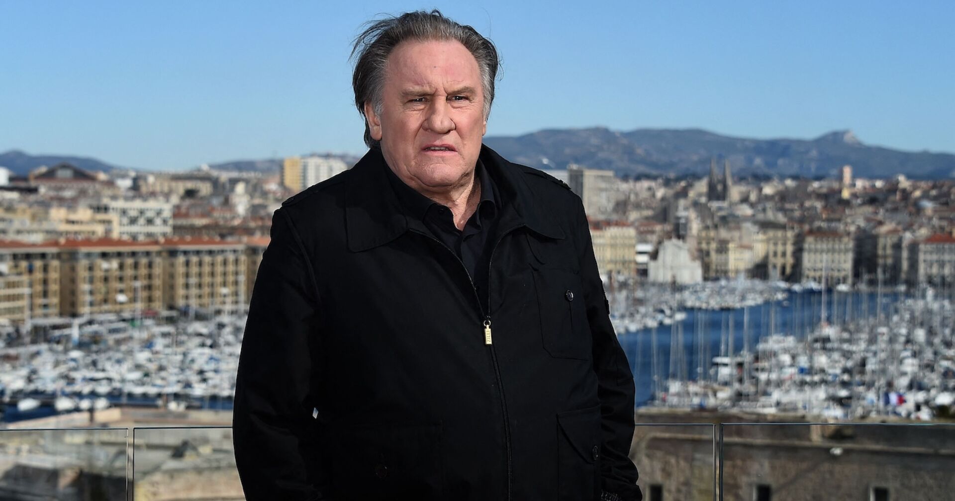 Gerard Depardieu auf einer Aussichtsplattform mit einem schwarzen Mantel.
