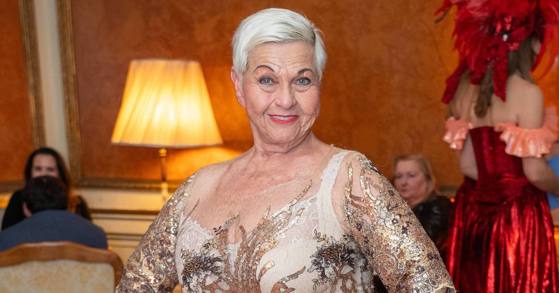 Jazz Gitti in einem goldenen Kleid mit kurzen blondierten Haaren.