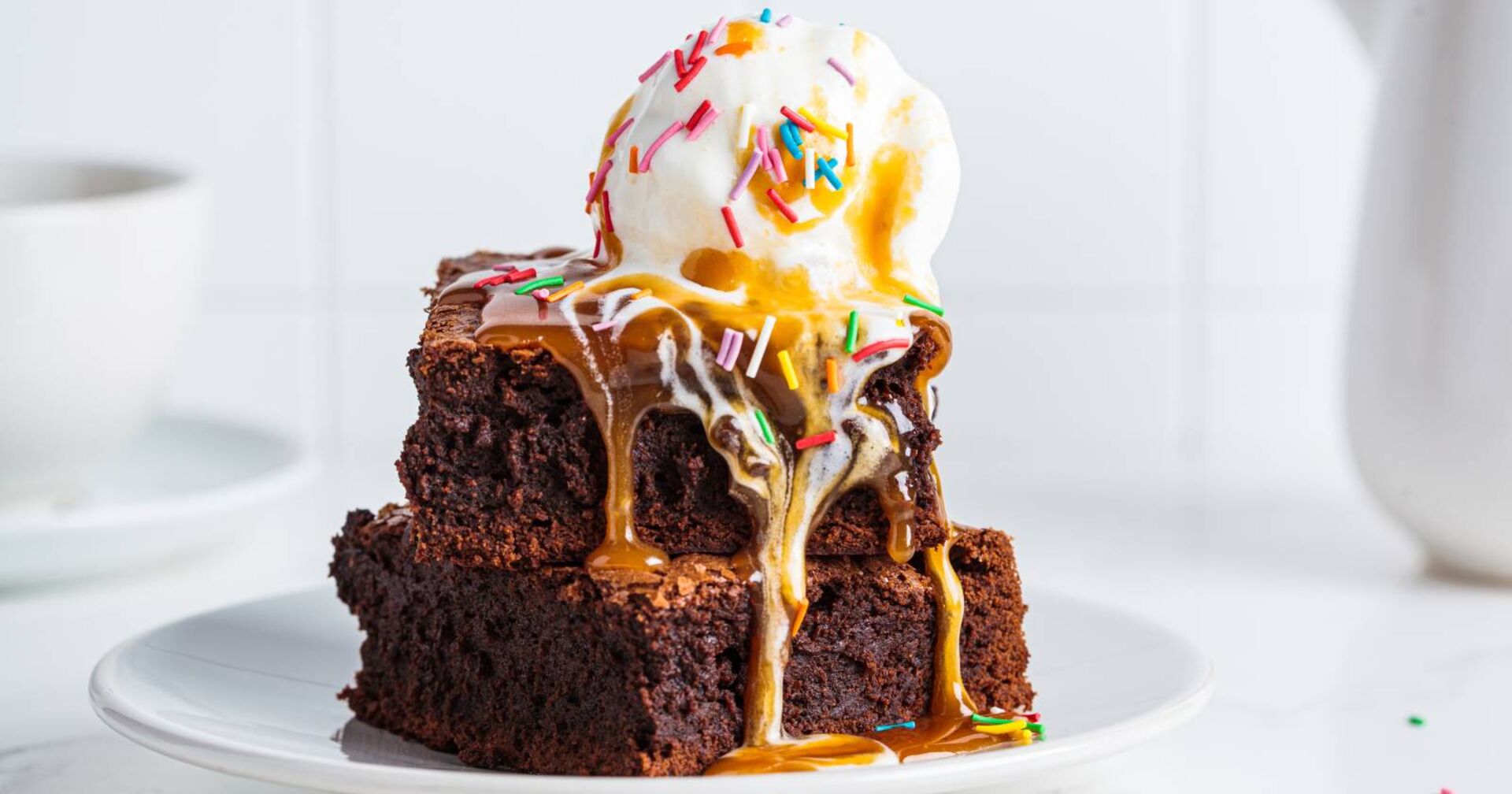 Aufeinander gestapelte Brownie-Stücke, serviert mit einer Kugel Vanilleeis und Karamellsauce