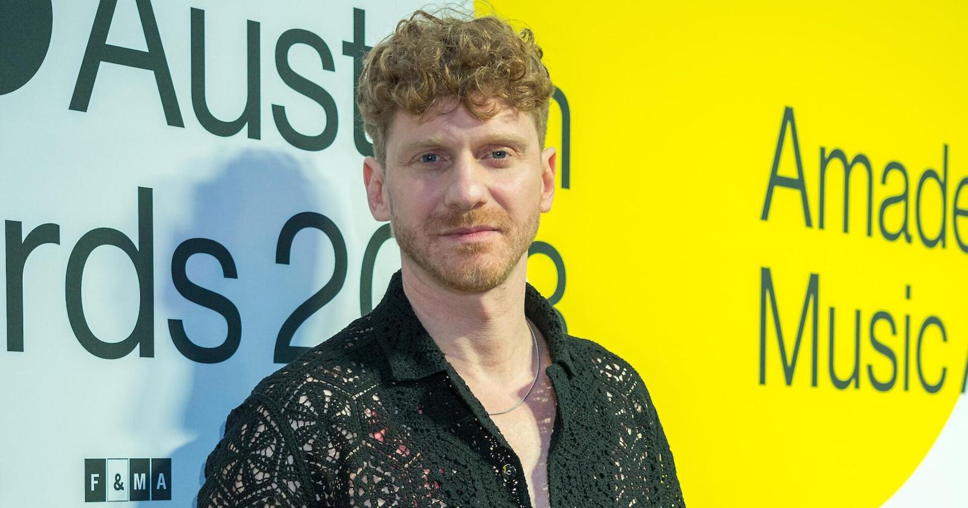 Lukas Fendrich in einem schwarzen Hemd vor einer Leinwand.