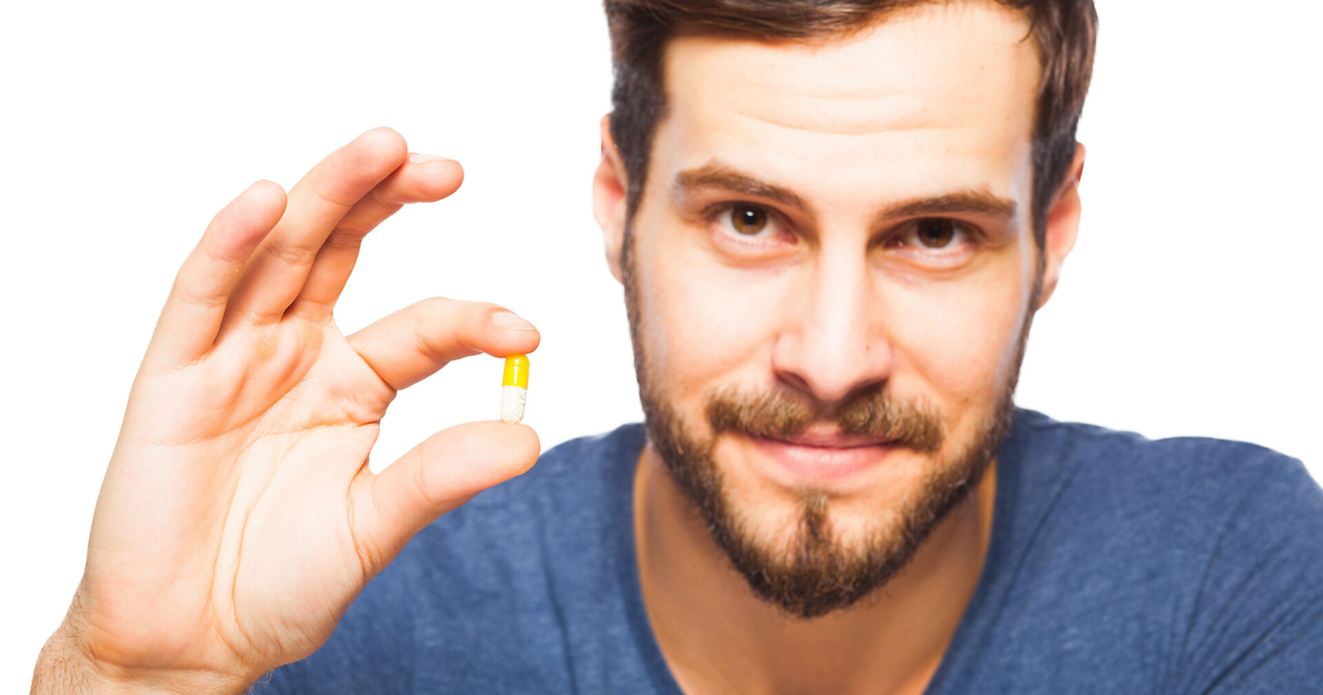junger Mann mit Bart hält eine Tablette in seinen Fingern