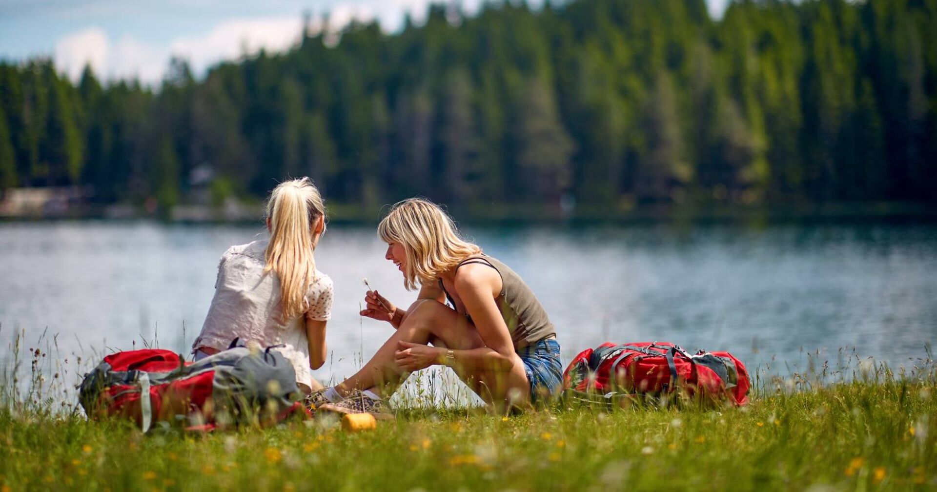 2 junge Frauen, die beim Ufer eines Sees sitzen