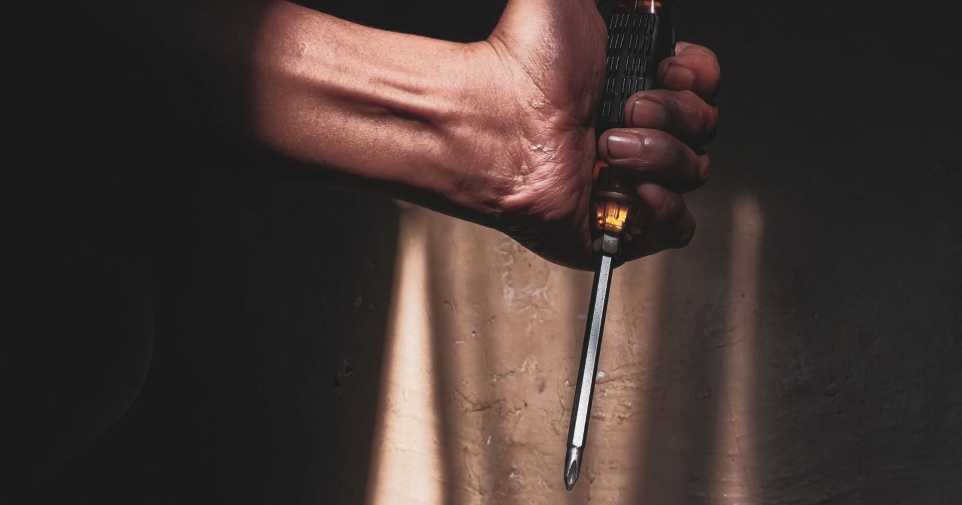 Ein Mann hält einen Schraubenzieher in der Hand.