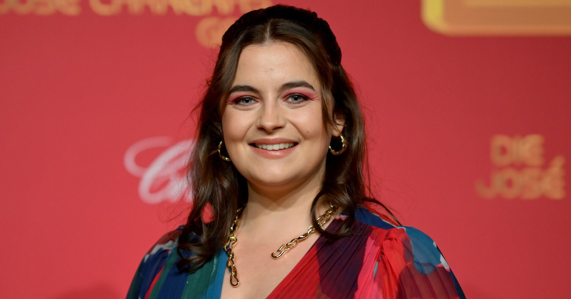 Ronja Forchter mit offenen braunen Haaren vor einer roten Fotowand.