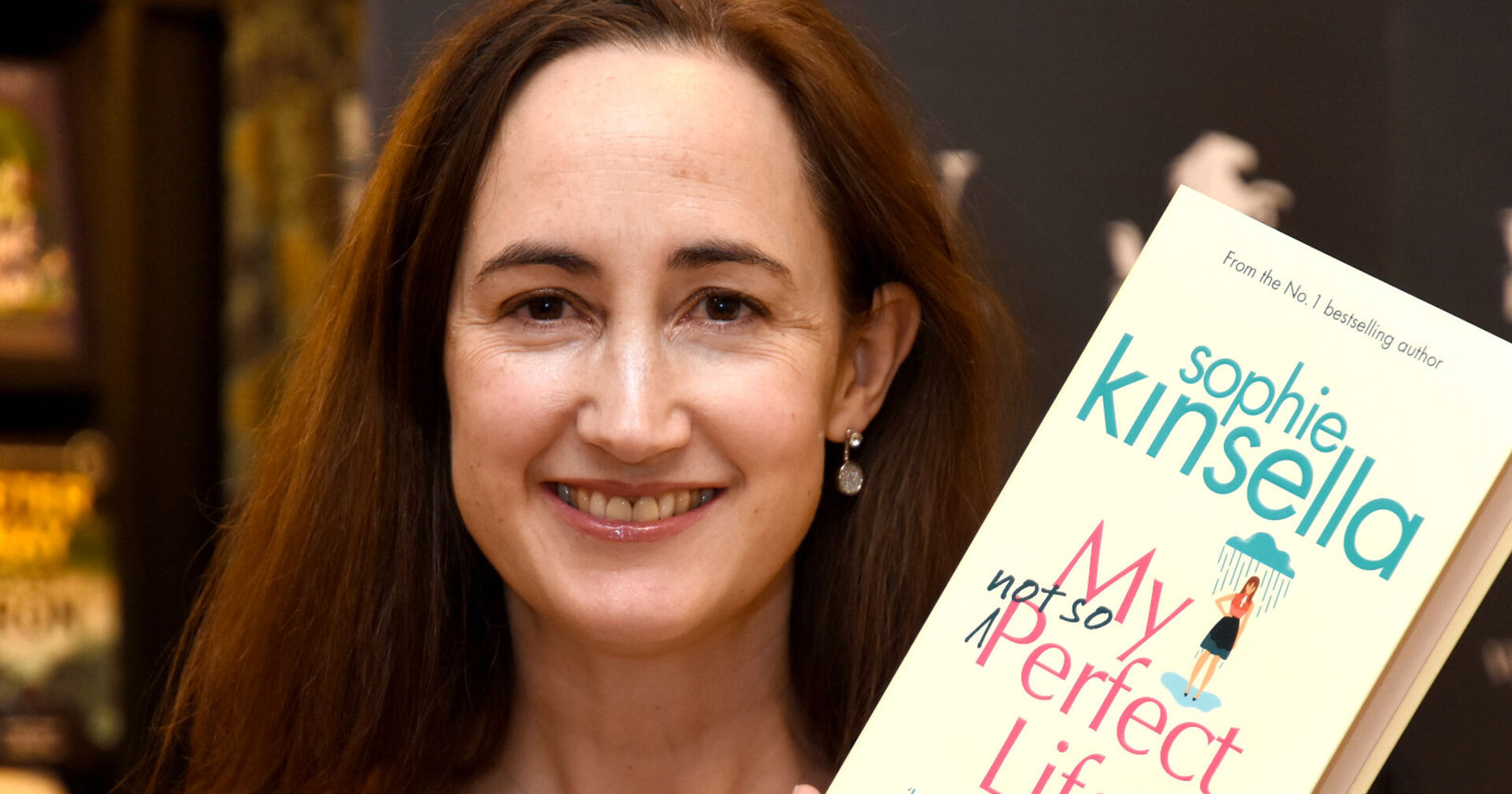 Eine lächelnde Frau hält ein Buch in die Kamera