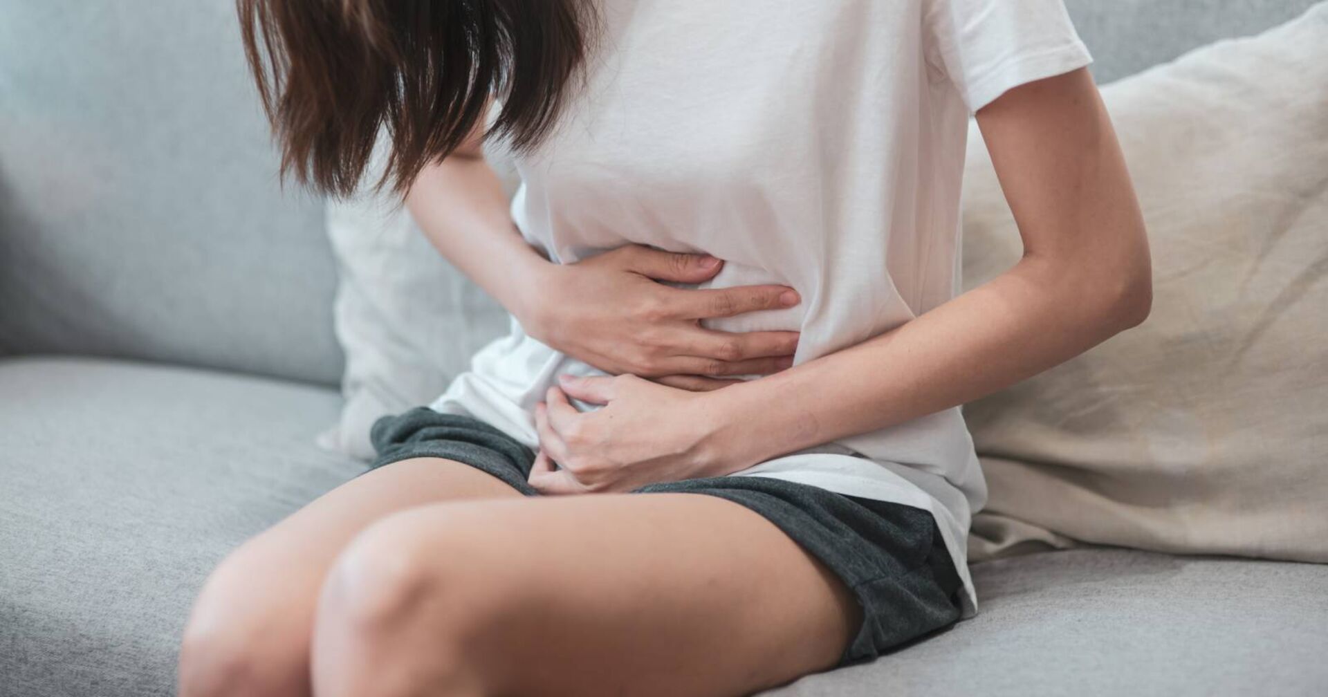 Frau, die sich wegen Regelschmerzen den Unterleib hält.