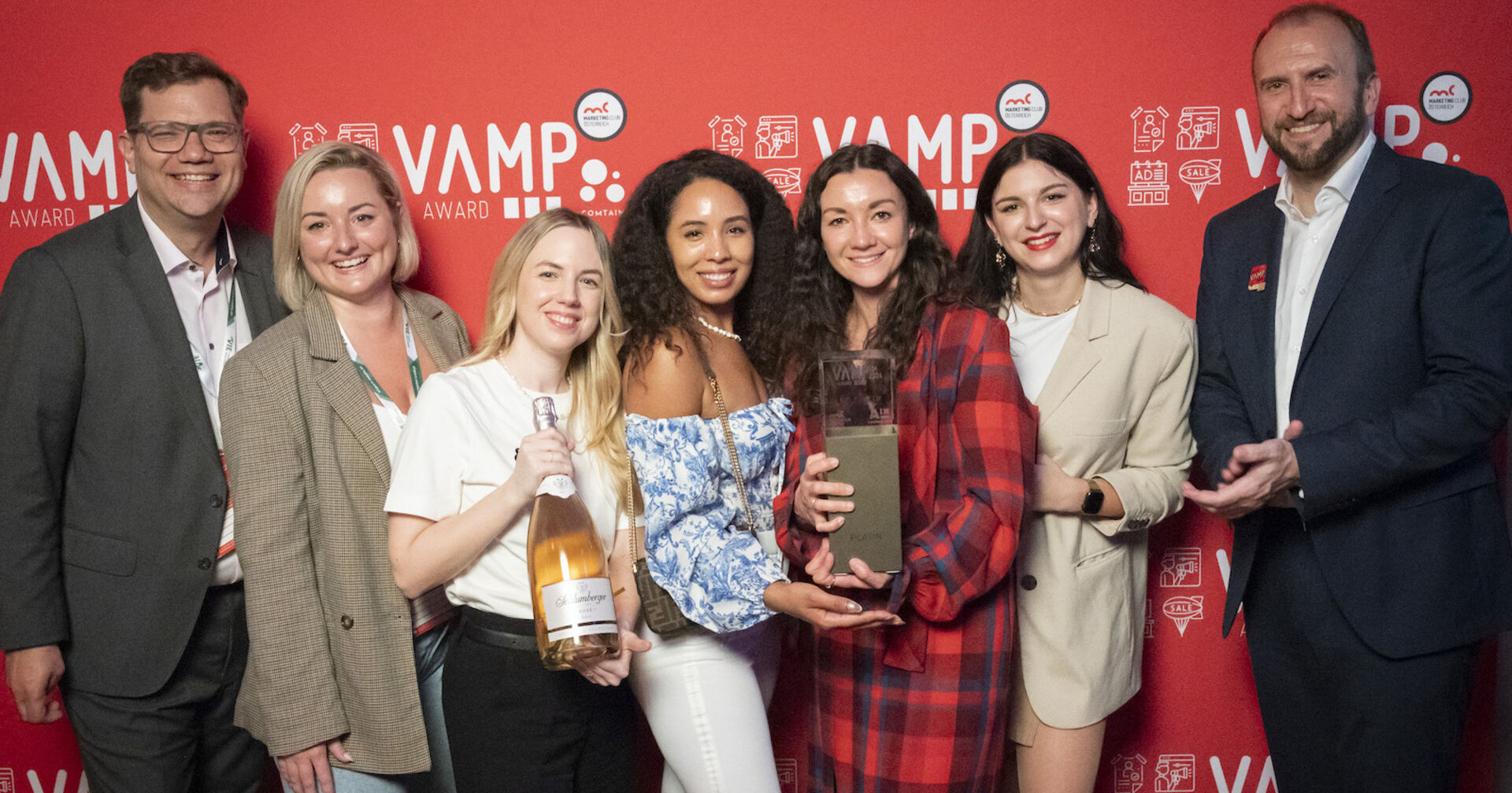 Platin-Award-Preisträger mit der Trophäe vor einer roten Wand