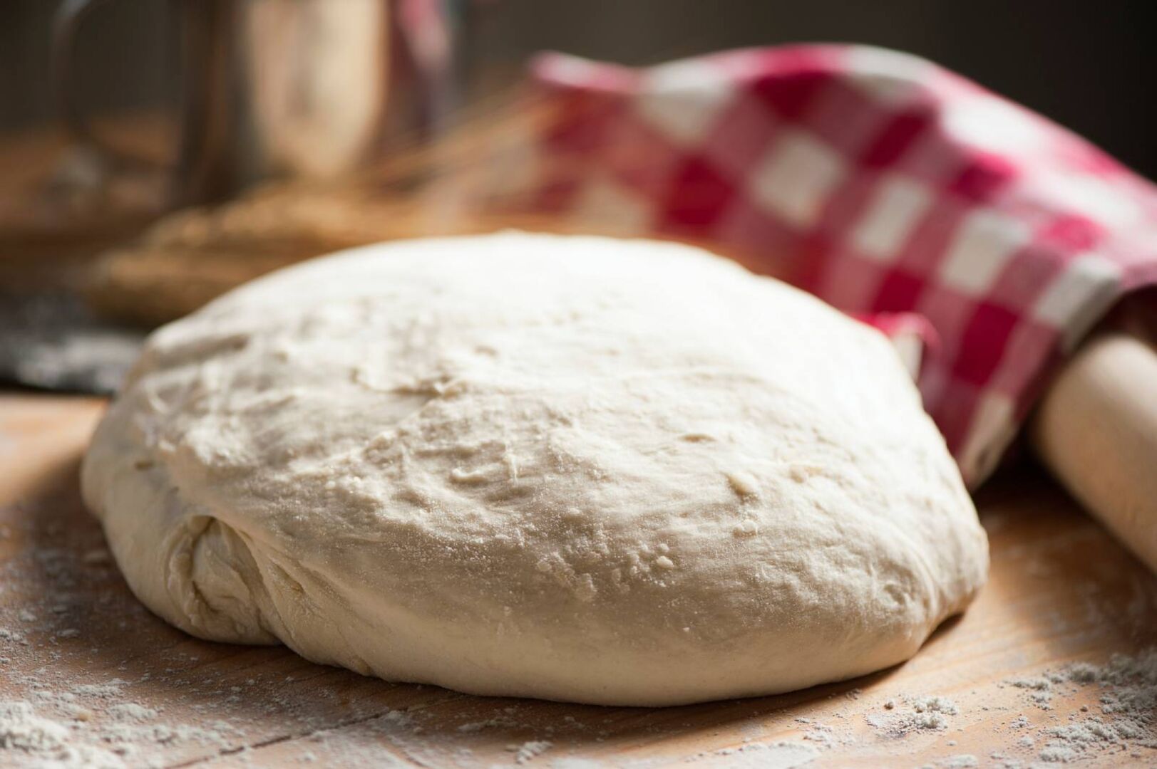 Ungebackener Brotlaib auf einem Holzbrett.