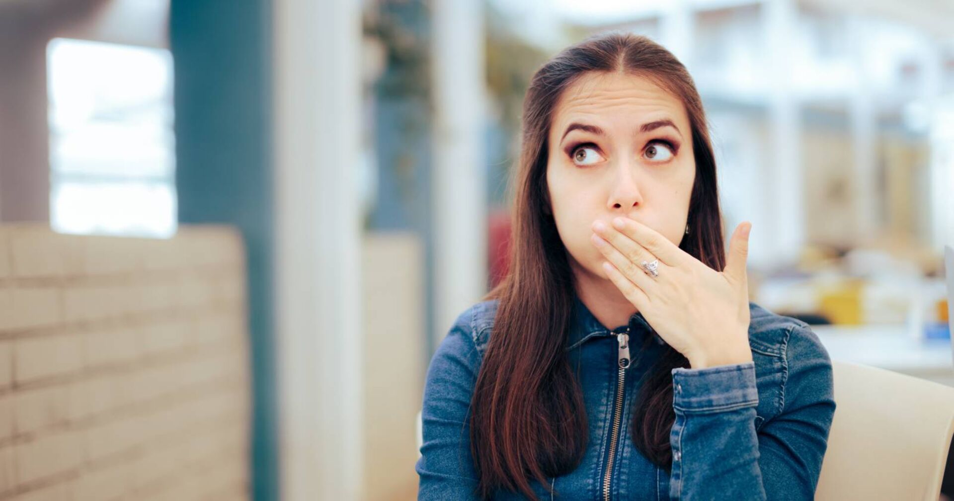 Junge Frau, die sich wegen eines Schluckaufs die Hand vor den Mund hält.