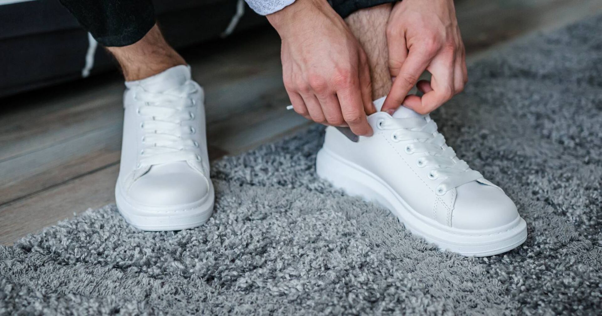 Weiße Sneakers, deren Schürsenkel gerade zugebunden werden