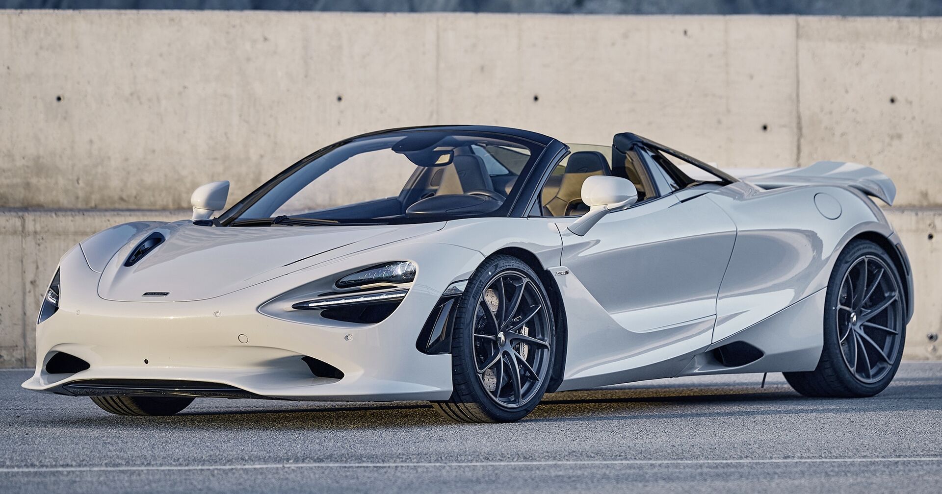 Ein weißes, aerodynamisch geformtes und sportliches Cabrio auf einem Parkplatz