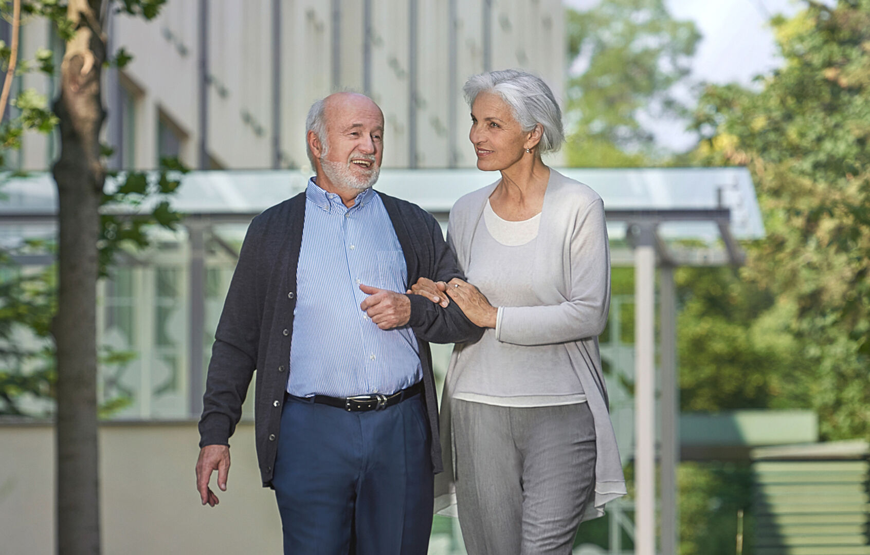 Pensionistin und Pensionist gehen miteinander Arm in Arm durch einen Park | Credit: Park Residenz Döbling