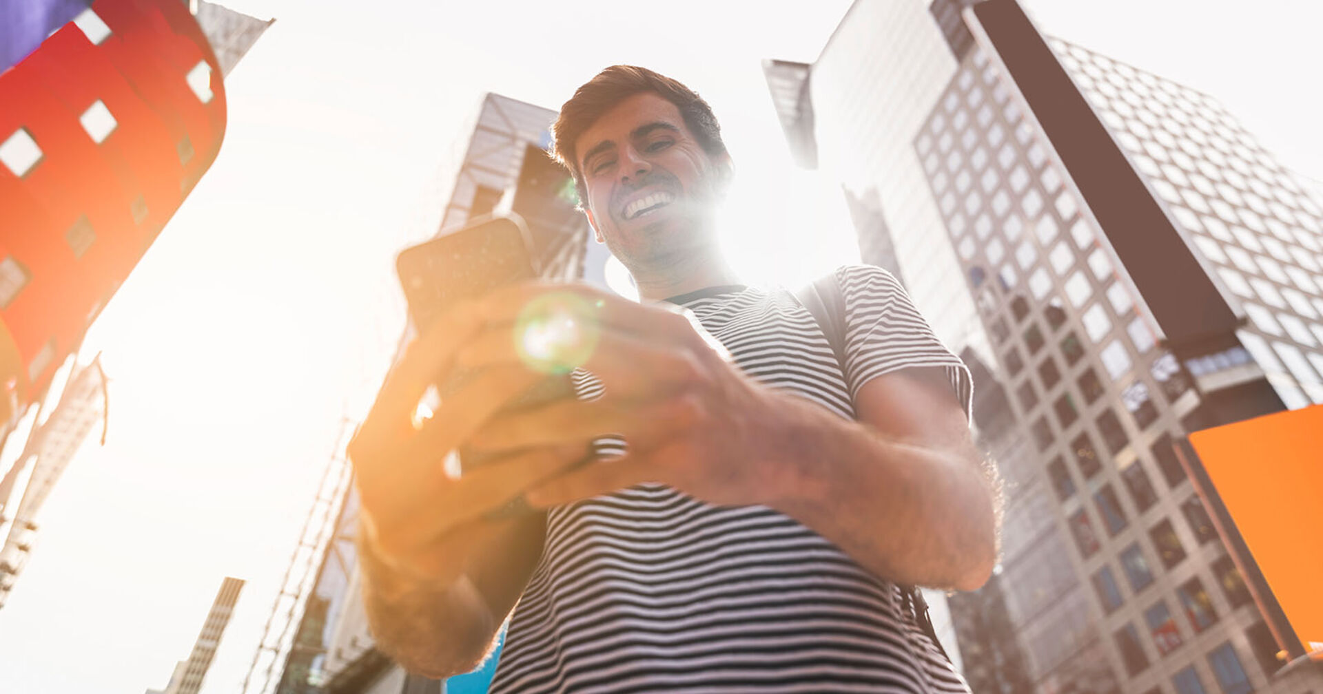 Ein Mann, der vor Hochhäusern in sein Smartphone schaut