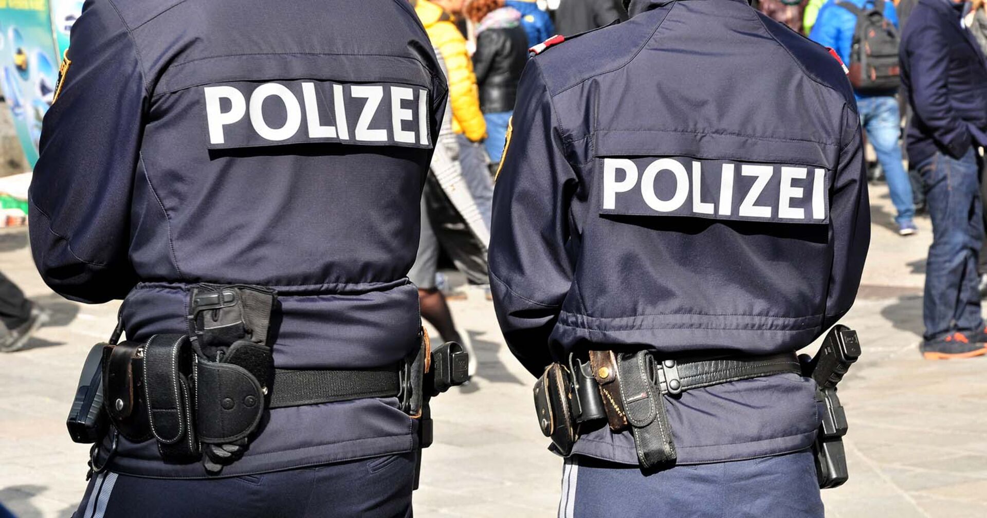 Zwei Polizisten, die mit dem Rücken zur Kamera stehen.