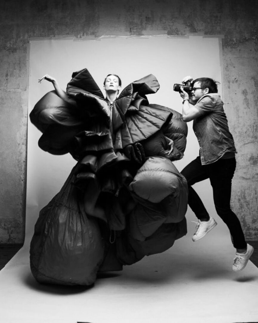 Ein Fotograf springt neben einem Model in einem wallenden Kleid