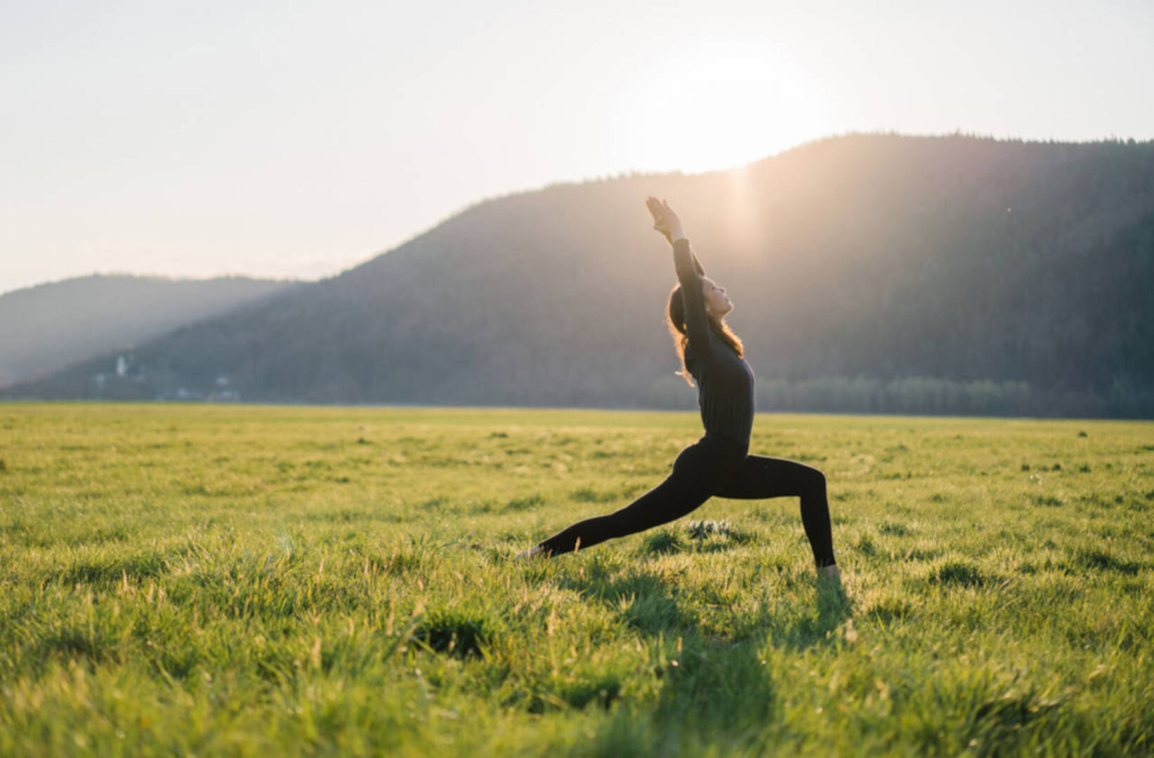 Eine Frau macht Yoga auf einer Wiese.