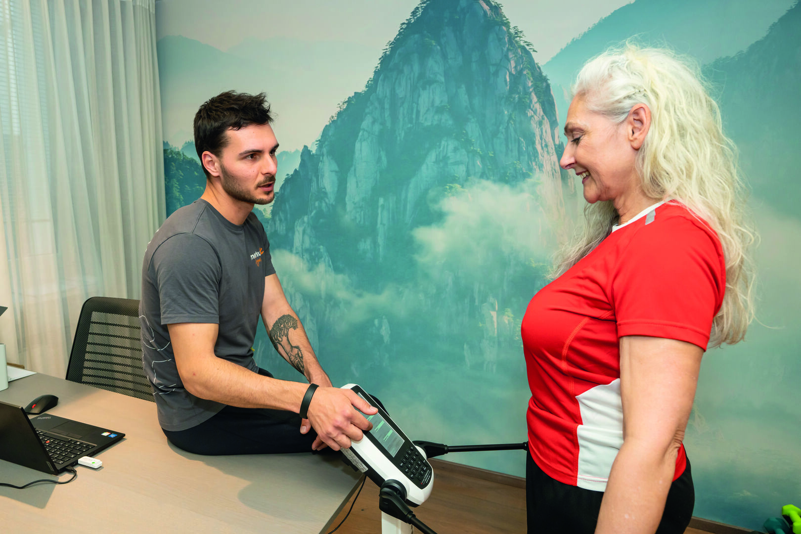 Trainer erklärt einer Frau etwas auf einem kleinen Bildschirm