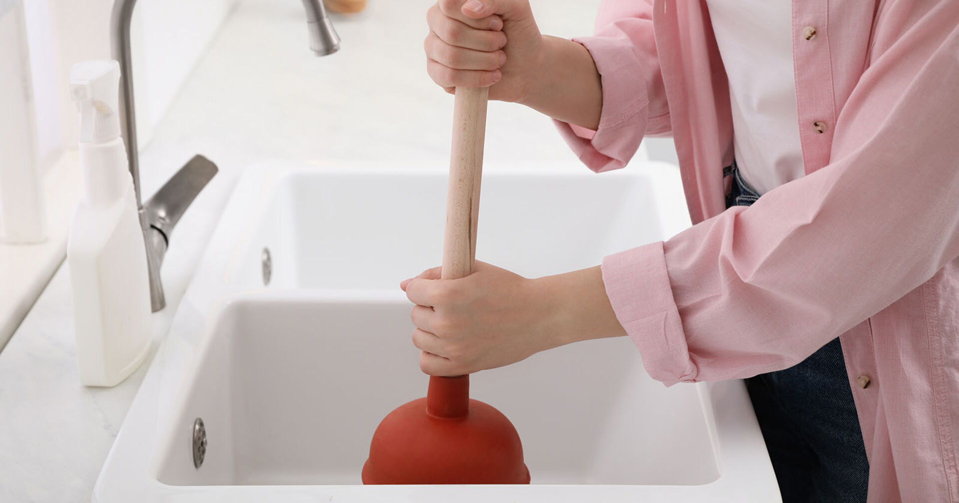 Frau behandelt verstopftes Rohr | Credit: iStock.com/Liudmila Chernetska